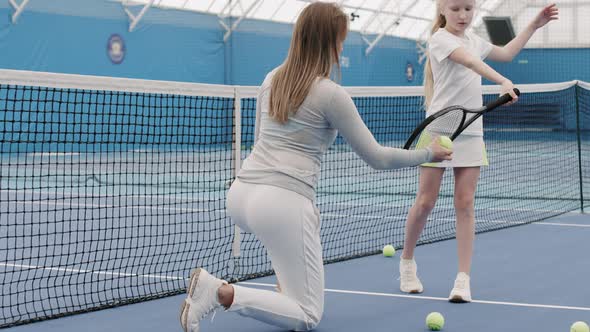 Girl Learning To Hit Tennis Ball On Court