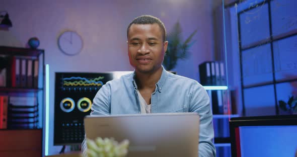 African American Man which Sitting in front of Laptop in Evening Office and Typing