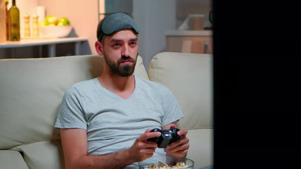 Close Up of Man with Eye Sleep Mask Playing Videogames with Joystick