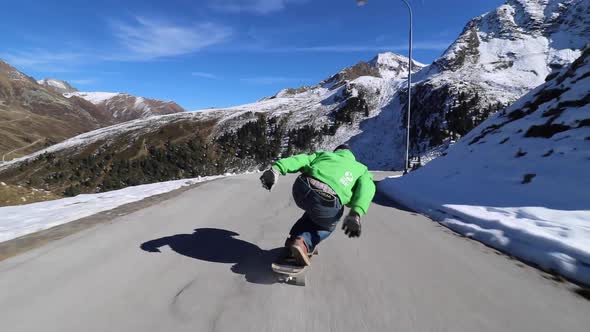 A man downhill skateboarding on a mountain road