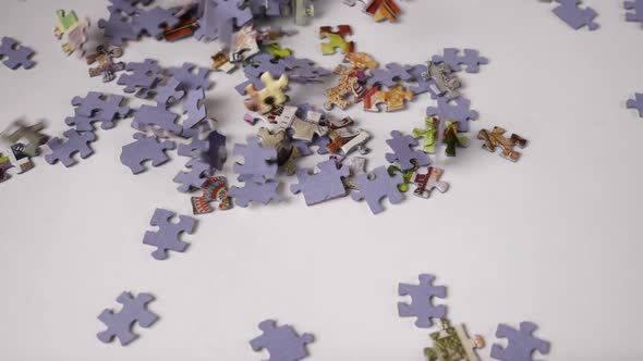 Slow Motion Puzzle Pieces Fall Haphazardly Onto a White Background Forming a Pile