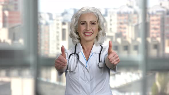 Senior Doctor Woman with Medical Coat and Stethoscope Shows Thumbs Up