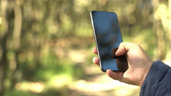 close up of a hand using a smarthphone in the forest