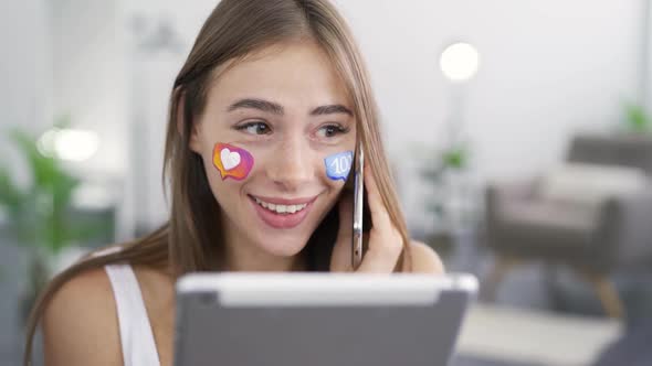 Portrait of Young Beautiful Woman with Painted Social Media Icons on Her Face Talking By Phone