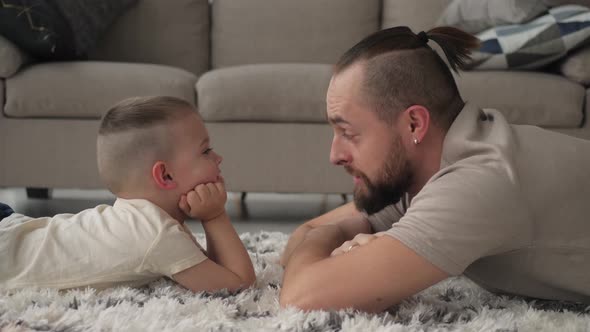 Family concept. Father and son lie down to talk on the floor of the house.