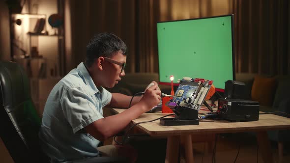 Boy Is Soldering Electronic Circuit And Works With Computer In Home, Mock Up Green Screen Display