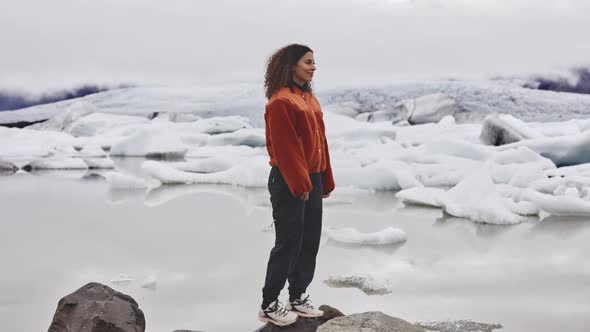 Woman Standing By the Rocks and Melting Ice By the Frozen Lake in Iceland