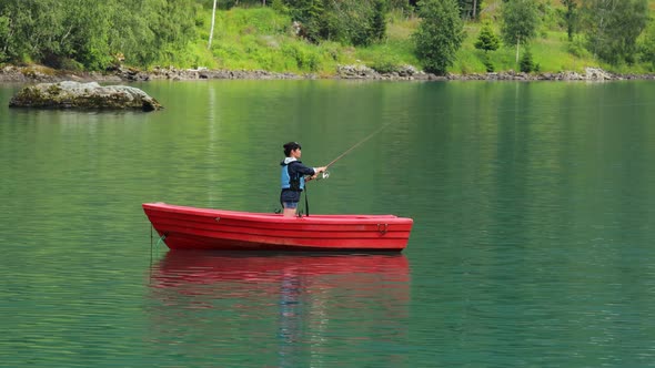 Woman on the Boat Catches a Fish on Spinning in Norway