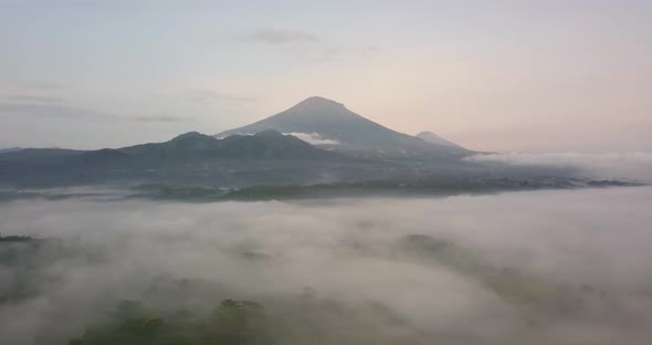 Mystic Aerial forward flight over tropical landscape covered with fog during sunny and cloudy day -