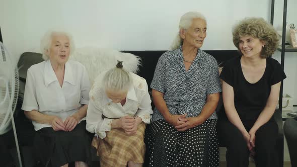 Portrait of Four Mixed Age Women on Sofa Looking and Smiling Into Camera in Room