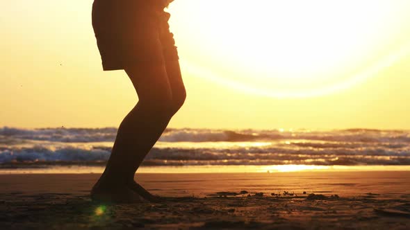 Silhouette of Girl's Legs Jumping on the Rope on the Sea Sand Beach at Sunset.