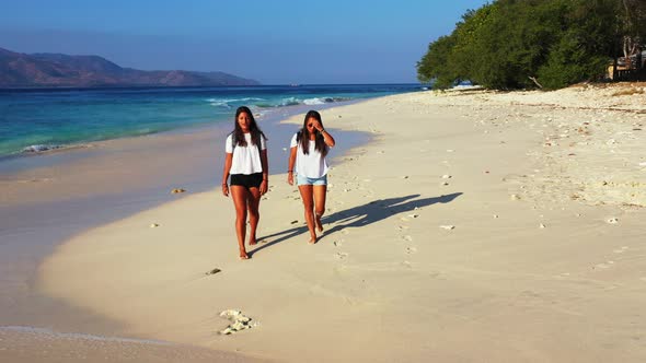 Sexy beauty models travelling spending quality time at the beach on clean white sand and blue backgr