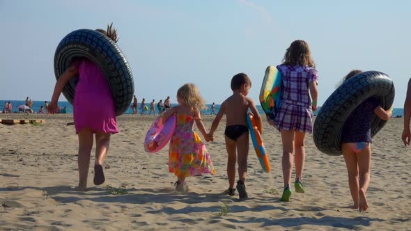 Children with Inflatable Swimming Tubes Go To the Sea