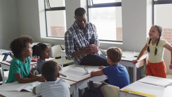 Video of happy african american male teacher and class of diverse pupils during biology lesson