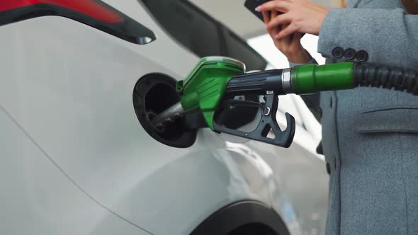 Woman Using Smartphone While Her Car Is Refueling. Slow Motion