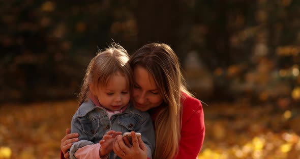 Mother and Daughter Using Smartphone in Park