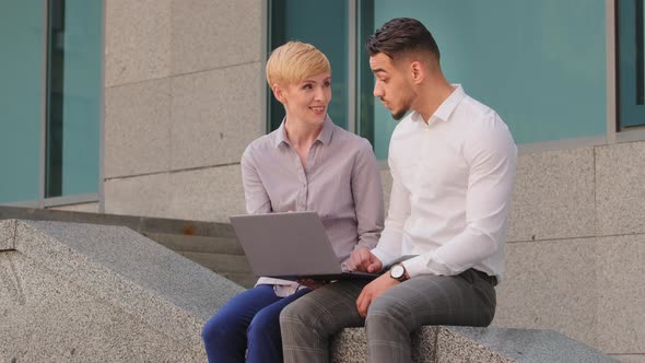 Multiethnic Colleagues Caucasian Woman and Arabic Hispanic Man Sitting Outdoors Looking in Laptop