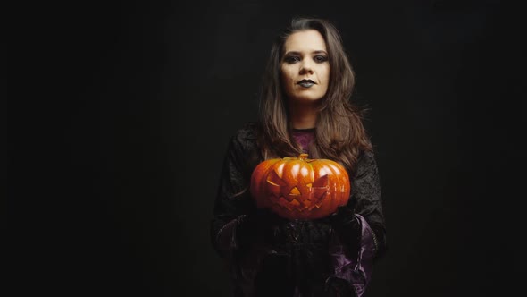 Young Woman Dressed Up Like a Witch Holding a Pumpking