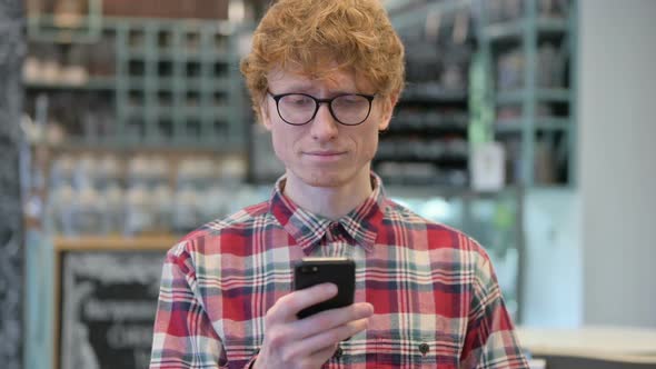 Attractive Young Redhead Man Using Smartphone