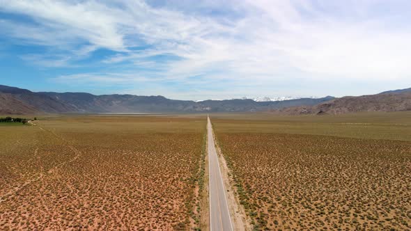 Hyper Lapse of Clouds Over Long Desert Road with Snowy Mountains