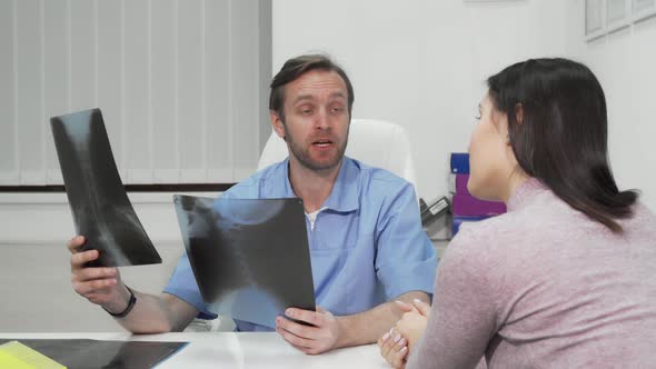 Mature Male Surgeon Examining X-ray Scans of a Female Patient