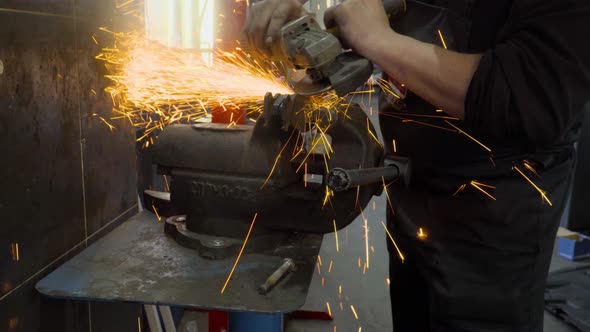 Closeup of worker using a grinder cuts metal in a workshop