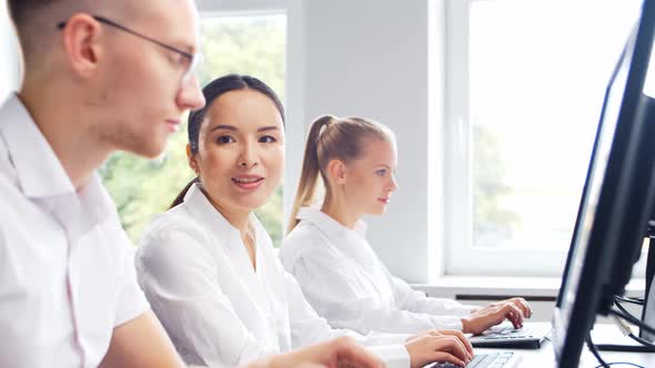 Diverse team of young professionals is working in the phone support office.