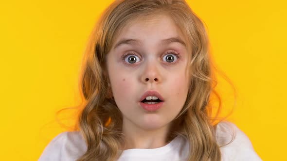 Small Schoolgirl Closing Eyes With Hands, Kid Is Afraid of Scary Movie, Close-Up