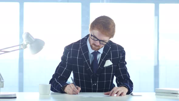 Redhead Businessman Paperwork, Writing and Working on Laptop