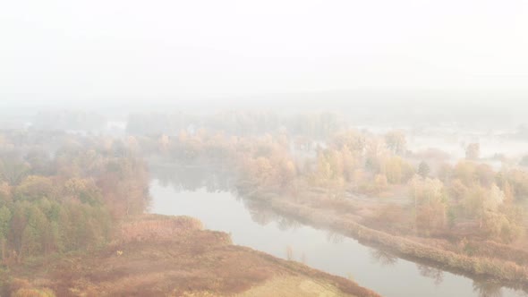 Low Flight Over a Misty Autumn River with Trees on the Banks in the Morning - Establishing Shot