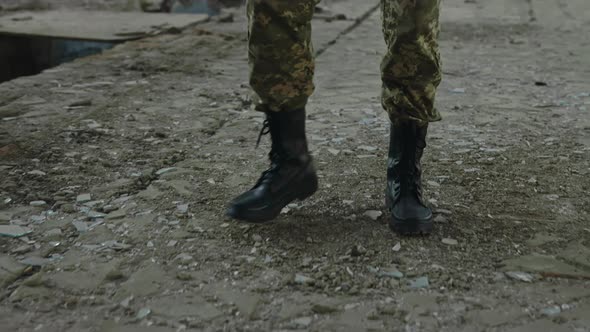 Soldier in Uniform and Boots Walking on Destroyed Factory