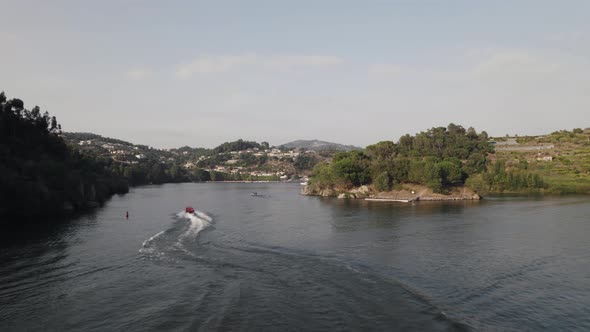 Aerial tracking of red motorboat sailing on river waters of Ilha dos Amores love Island