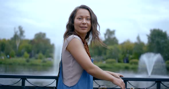 Smiling Happy Girl Is Admiring Fountain in Park in City in Summer Day