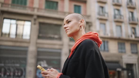 Positive bald woman texting by phone