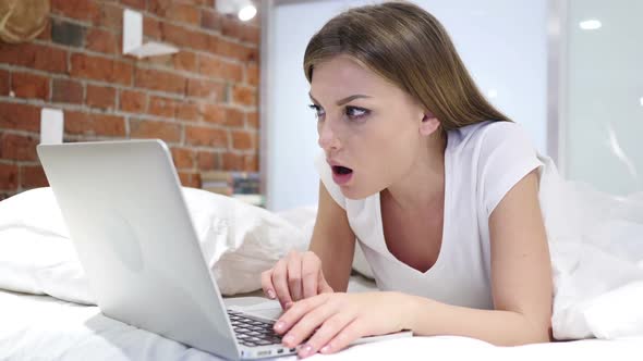 Woman in Bed in Shock By Results on Laptop Wondering