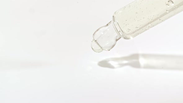 Macro Shot of Transparent Yellow Cosmetic Fluid Gel Cream With Bubbles in Pipette Drips on a White