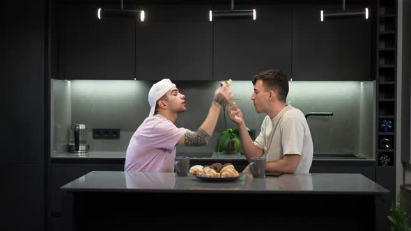 Side View Caucasian LGBTQ Couple in Kitchen at Home Talking Eating Sweet Dessert