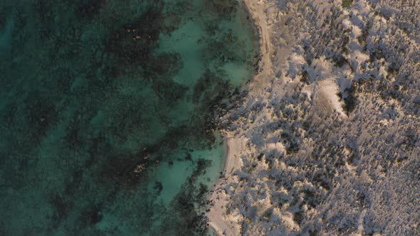 Aerial Top Down Flyover Shot of Deserted Beach in Cyprus. Flying at Sunset Above Coast