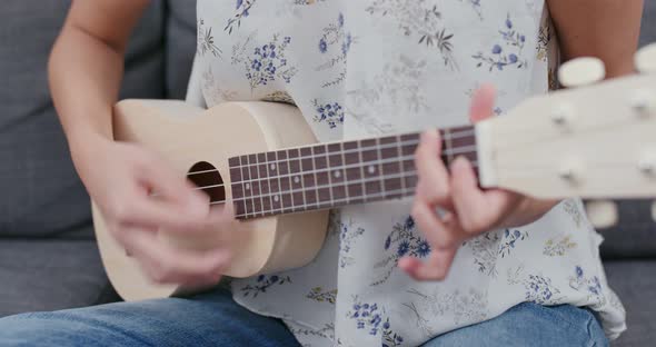 Woman play ukulele at home