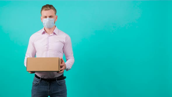 Man Wearing Face Mask While Holding a Package and Standing in the Studio.