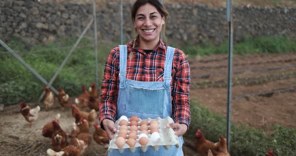 Senior farmer woman picking up organic eggs in henhouse - Farm lifestyle and healthy food concept
