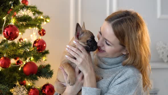 Young Woman Holds a Dog in Herhands