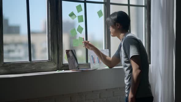 Pensive Young Asian Man Thinking on Business Startup Idea Analyzing Graphs and Online Data on Laptop