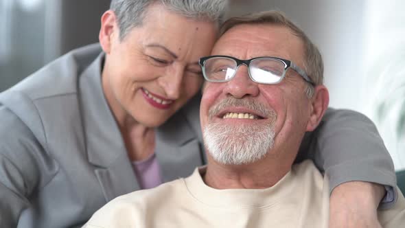 Beautiful Grayhaired Couple Hugging While Sitting on the Couch