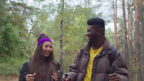 Multiracial Couple Trekking in Forest Together