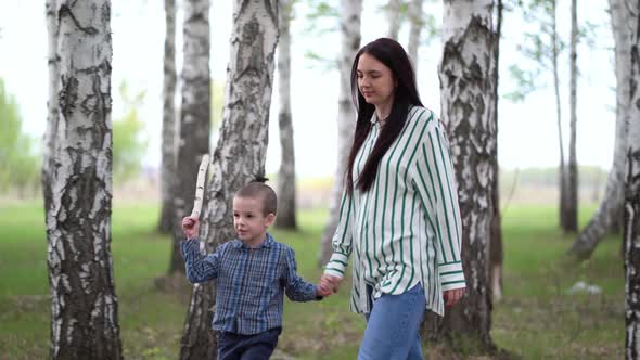 Mother and Son Walk in a Birch Grove on a Spring Day