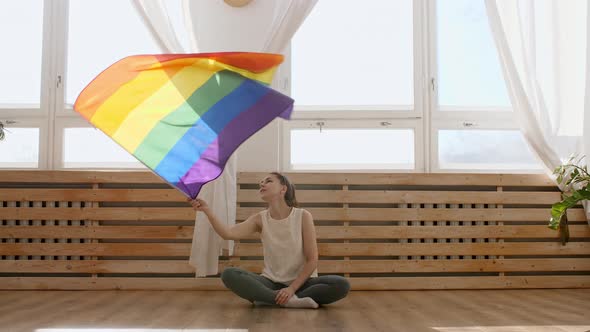 Female Holding LGBT Gay Flag in Hands and Waving on Sunset in Sunny Rays