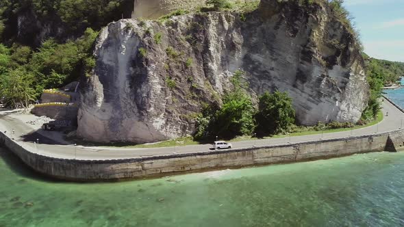 Aerial view of white car driving on coastline in Oslob, Philippines.