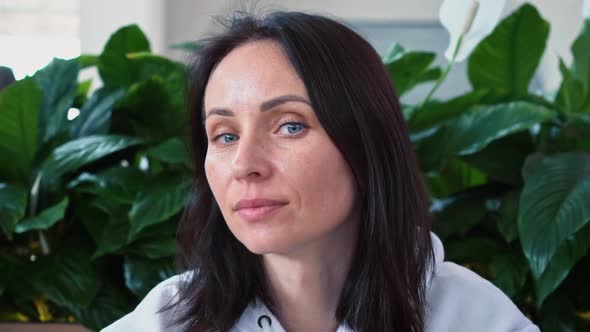 A Young Beautiful Brunette Woman of Caucasian Nationality in a White Sweater Sits in a Cozy Zone