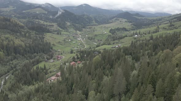 Village in the Mountains. Slow Motion. Carpathians. Ukraine. Aerial. Gray, Flat